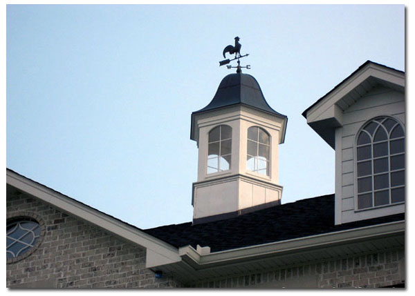 paddock cupola with windows and rooster on a large brick house close up